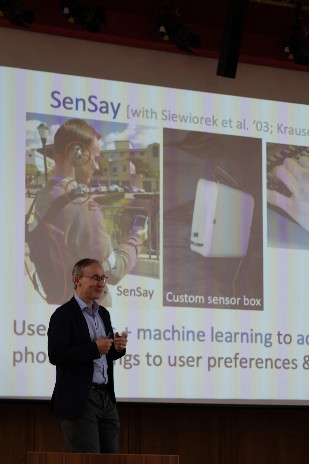 Professor Andreas Krause speaking on stage in front of a research slide titled SenSay.